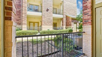 A view of a courtyard from a doorway with a black metal fence.